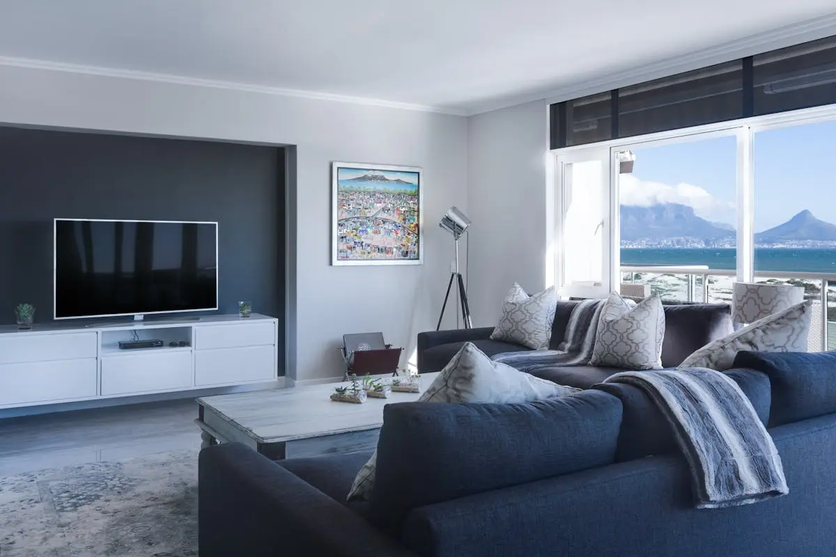 Adult adjusting TV volume from the couch — a common scenario when hearing loss begins to affect home listening