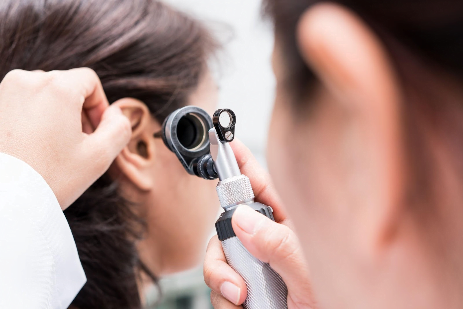 Hearing care specialist using an otoscope to examine a patient's ear during a diagnostic hearing evaluation