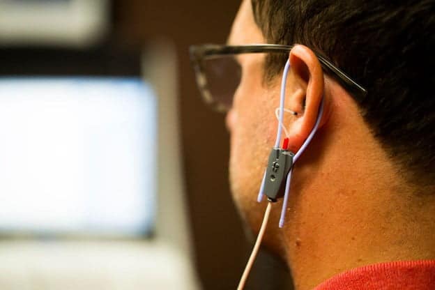 Close-up of a man's left ear fitted with a real-ear measurement probe microphone during a hearing aid verification