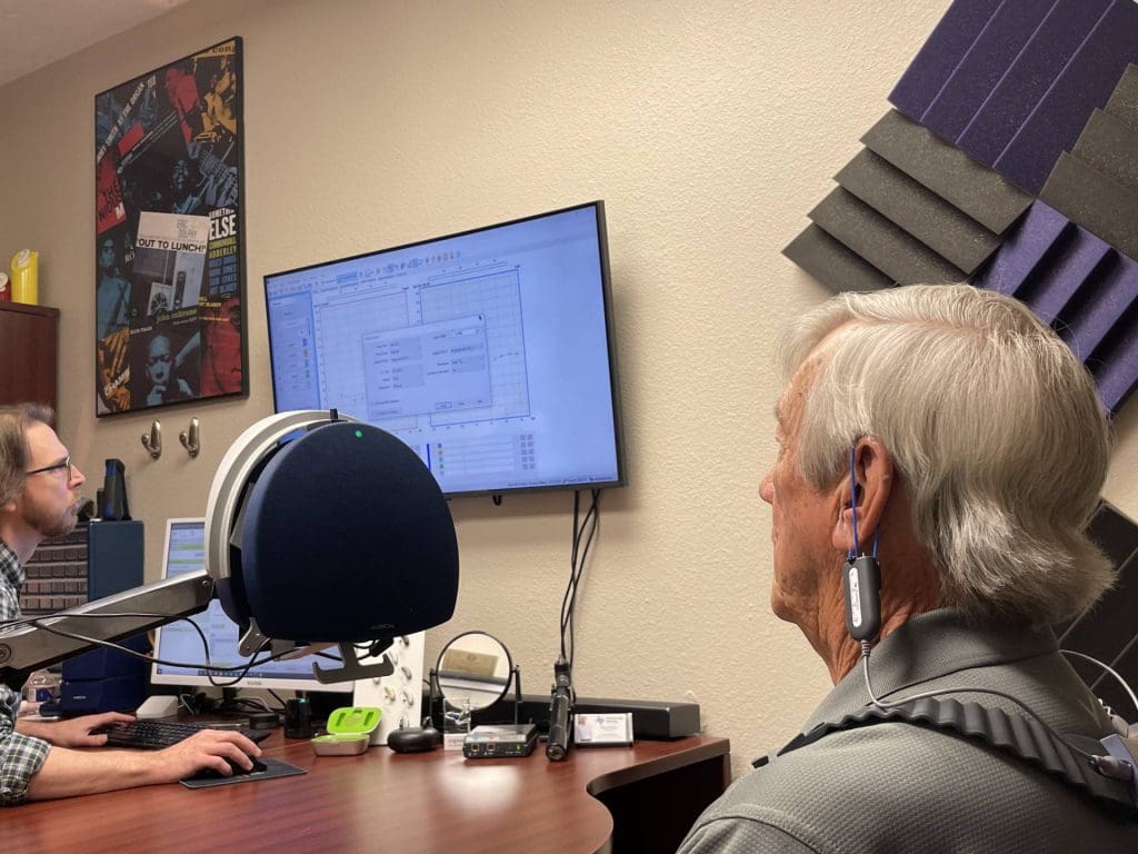 a man having his hearing aid performance evaluated with Real Ear Measurement