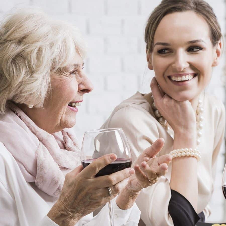 An older woman and younger woman share a glass of wine and enjoy conversation
