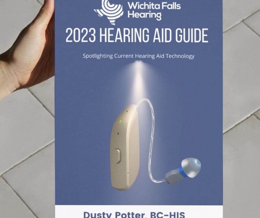 A person holds a printed version of the 2023 Hearing Aid Guide